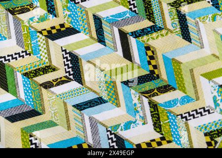 Una trapunta con motivo a freccia verde e bianco. La trapunta è composta da molti pezzi diversi di tessuto, e i colori sono luminosi e allegri. T Foto Stock