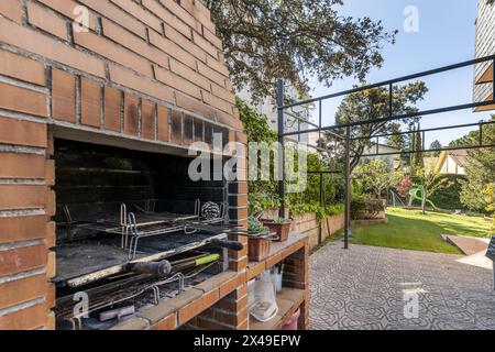 barbecue incorporato con vigne da giardino con un sentiero piastrellato e un giardino con erba sullo sfondo Foto Stock