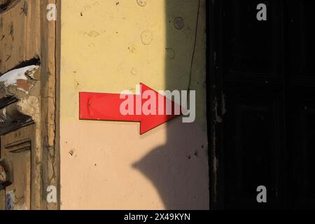 Sul muro giallo della casa c'è una freccia rossa rivolta verso destra nell'ombra Foto Stock