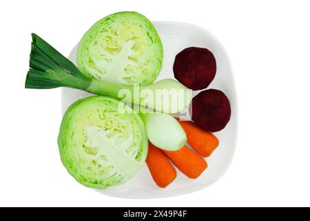 Cavolo, carote, barbabietole e cipolle in un piatto isolato su fondo bianco. Verdure sbucciate per cucinare in casa. Cibo sano fatto in casa. Foto Stock