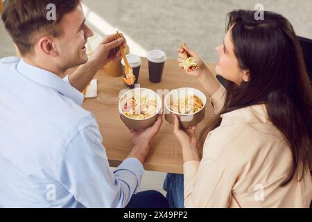 I giovani e le donne felici stanno parlando felicemente mentre si gustano deliziosi piatti da asporto. Foto Stock