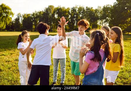 Gruppo di bambini felici che si divertono a divertirsi a vicenda con cinque camminate nel parco estivo. Foto Stock