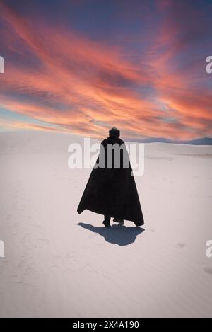 Una persona che indossa un mantello nero e un copricapo turbante nero contempla la vista delle dune di gesso tra il cielo al White Sands NP di Alamogordo, NEW MEXICO Foto Stock