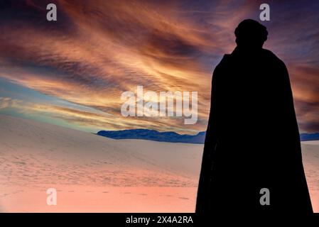 Una persona che indossa un mantello nero e un copricapo turbante nero contempla la vista delle dune di gesso tra il cielo al White Sands NP di Alamogordo, NEW MEXICO Foto Stock