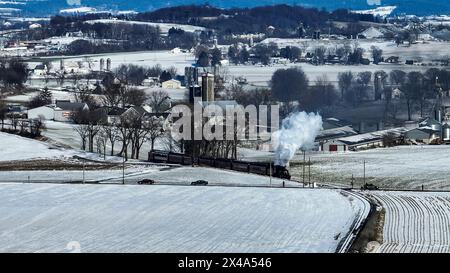 Un treno sta viaggiando attraverso una campagna innevata. Il treno è bianco e nero ed è l'unica cosa visibile nell'immagine Foto Stock