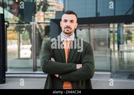 Giovane uomo ben vestito con un'espressione seria e premurosa. Primo piano ritratto individuale di un bellissimo barbuto che guarda davanti con sicurezza, guardando la fotocamera in piedi all'aperto. Foto di alta qualità Foto Stock
