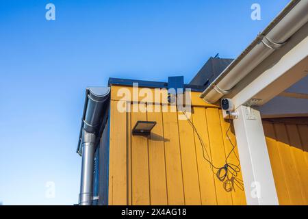 Vista ravvicinata di una telecamera di sicurezza esterna e di una lampada da esterno con pannelli solari sulla facciata di una villa in una giornata di sole. Svezia. Foto Stock