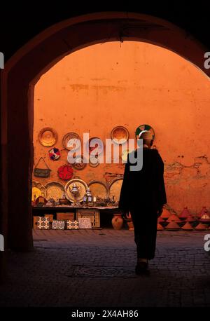 Marocco, Medina di Marrakech. Una strada stretta e colorata e un arco nella kasbah. Un uomo locale irriconoscibile cammina attraverso l'arco. Patrimonio mondiale dell'UNESCO. Foto Stock