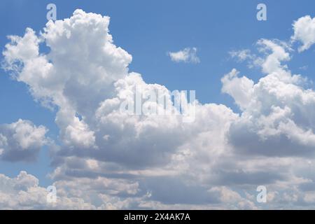 Un aereo che vola attraverso un cielo pieno di soffici nuvole bianche in una giornata di sole. Foto Stock