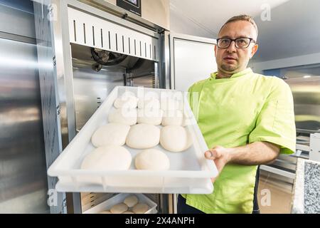 lo chef tiene le palle di impasto per pizza verso la macchina fotografica nella pizzeria. Foto di alta qualità Foto Stock