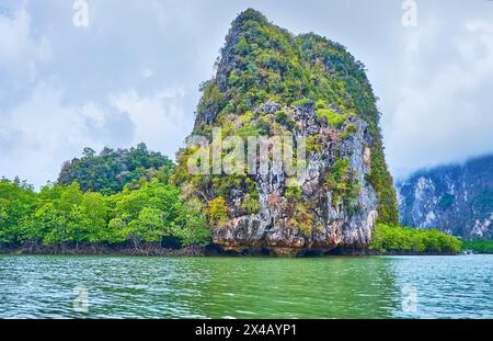 La gita in barca lungo la costa dell'isola di Ko Thalu OK con alte rocce, foreste tropicali e mangrovie, Phang Nga Bay, Thailandia Foto Stock