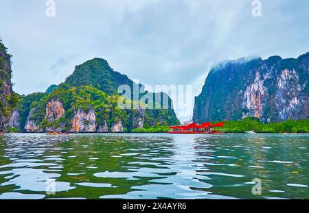 Le ripide rocce, le mangrovie e la nave turistica ormeggiata sulla costa dell'isola di Ko Thalu OK, Phang Nga Bay, Thailandia Foto Stock