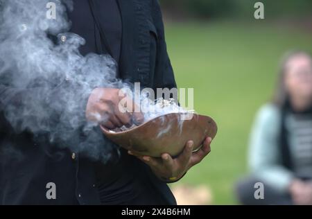 Fuoco rituale con ramo in fiamme verdi, fumo e fuoco, il rito rituale del fumo in un evento della comunità indigena in Australia Foto Stock