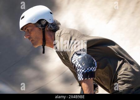 Skateboarder brasiliano di 54 anni che si diverte in uno skate Park in una giornata di sole 11. Foto Stock