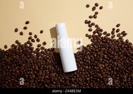 Sfondo vuoto per pubblicizzare prodotti cosmetici con ingredienti di caffè. Chicchi di caffè decorati con bottiglia cosmetica bianca senza etichetta per design p Foto Stock