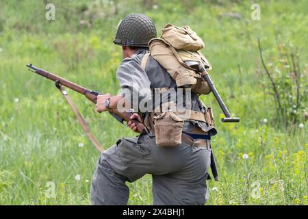 La fanteria dell'esercito AMERICANO durante la seconda guerra mondiale corre ad attaccare con un fucile. Ricostruzione storica Foto Stock