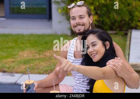 Coppie diverse che si godono un drink all'aperto, sedute a casa, spazio fotocopie. Lui, avendo la pelle leggera e i capelli castani, tenendo il vetro, mentre lei, con la pelle d'oliva Foto Stock