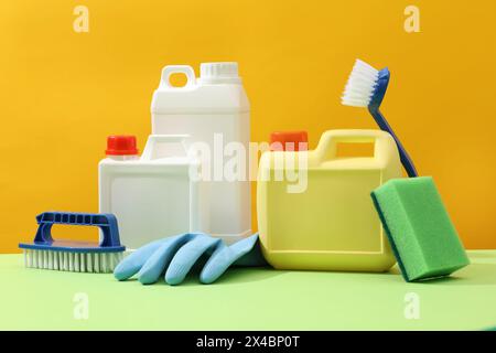 Set di pulizia per superfici diverse in cucina, bagno e altre camere. Taniche in plastica vuote visualizzate su sfondo giallo con pennelli blu, da a Foto Stock