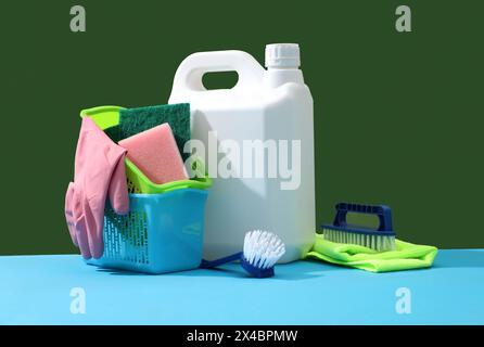 Cestello con detergenti, guanti in gomma, spugne, spazzole blu e panni decorato su sfondo colorato. Etichetta vuota in plastica bianca per il design. K Foto Stock