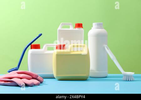 Prodotti per la pulizia colorati decorati su sfondo verde. Set di detergenti diversi con spazzole e guanti esposti. Concetto di professione Foto Stock