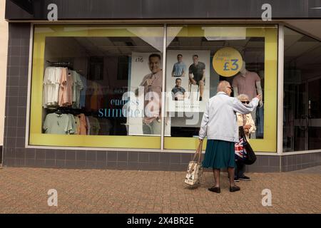 Due signore anziane alla vetrina espongono abiti di PAVONI a Leighton Buzzard, Bedfordshire, Inghilterra, Regno Unito Foto Stock