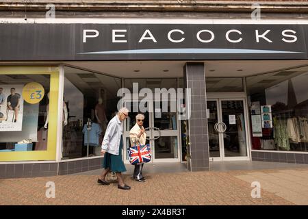 Due signore anziane alla vetrina espongono abiti di PAVONI a Leighton Buzzard, Bedfordshire, Inghilterra, Regno Unito Foto Stock