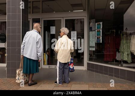 Due signore anziane alla vetrina espongono abiti di PAVONI a Leighton Buzzard, Bedfordshire, Inghilterra, Regno Unito Foto Stock