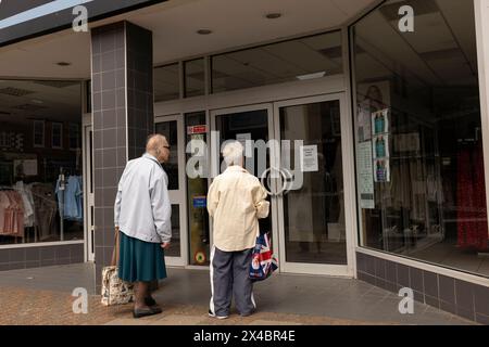 Due signore anziane alla vetrina espongono abiti di PAVONI a Leighton Buzzard, Bedfordshire, Inghilterra, Regno Unito Foto Stock