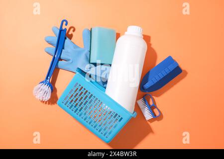 Vari articoli per la pulizia includono: Spazzola, guanti in gomma flacone di detergente e cestelli in plastica su sfondo rosso. Mockup pubblicitario per prodotti per la pulizia Foto Stock