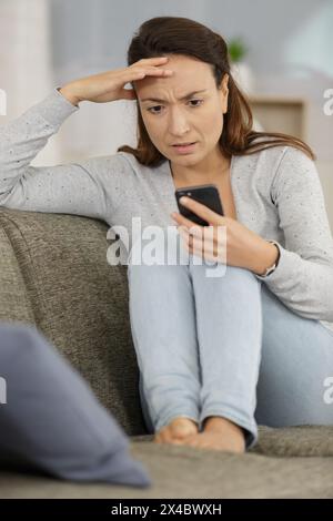 donna arrabbiata in attesa di una chiamata su smartphone Foto Stock