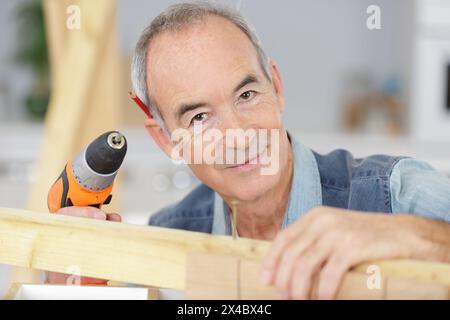 carpentiere senior con un cacciavite a batteria Foto Stock