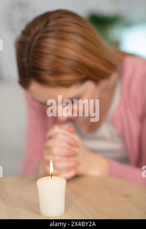 la giovane donna caucasica prega con una candela Foto Stock