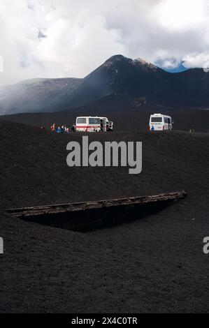 A 2.900 metri sul livello del mare, sull'Etna in Sicilia, Italia, veicoli per escursioni fuoristrada e turisti con, in primo piano, il Rifugio Torre del filosofo, sepolto in torrenti di lava fredda (sciare). Foto Stock