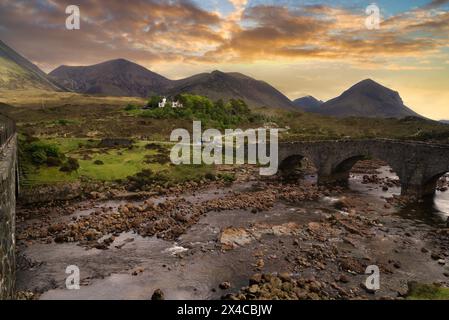 Guardando verso sud-ovest lungo il fiume Sligachan al "Ponte Vecchio". Turisti. Fiume incorniciato contro le montagne Cuillin. Skye. Highlands occidentali, Scozia Foto Stock