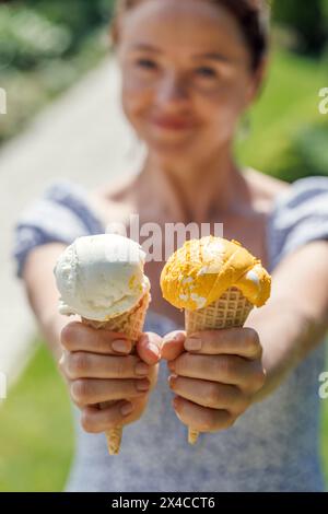 Le mani delle donne tengono un gelato rinfrescante in coni di waffle con un pizzico di saporito sapore di limone Foto Stock