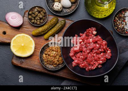 Cottura di una saporita tartare di manzo con cetriolini sottaceto e pane tostato. Spianatura piatta Foto Stock