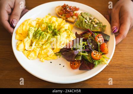 Un nutriente brunch servito con soffici uova strapazzate, una vibrante insalata mista, pane tostato all'avocado e semi Foto Stock
