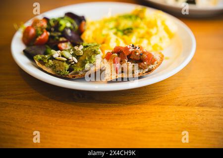 Un nutriente brunch servito con soffici uova strapazzate, una vibrante insalata mista, pane tostato all'avocado e semi Foto Stock