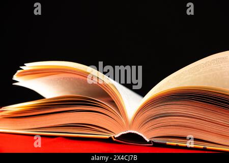 Le pagine di un libro spesso vengono attivate su uno sfondo rosso e nero. Foto Stock