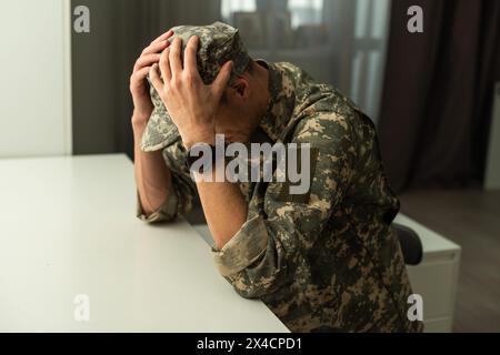 Un soldato sconvolto che gli copre la faccia, forse soffre di shock da conchiglia o disturbo da stress post traumatico Foto Stock
