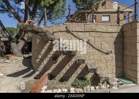 Scale esterne di una casa indipendente con traversine in legno integrate in un muro curvo su una proprietà con terreni sabbiosi Foto Stock
