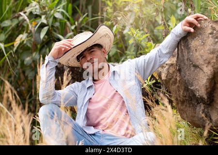 stile di vita: contadino latino seduto in campo con seria espressione Foto Stock