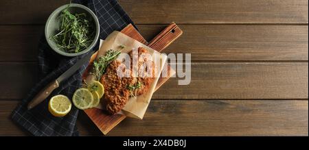 Gustosi schnitzels serviti con limone e microgreen su un tavolo di legno, piatto. Design banner con spazio per il testo Foto Stock