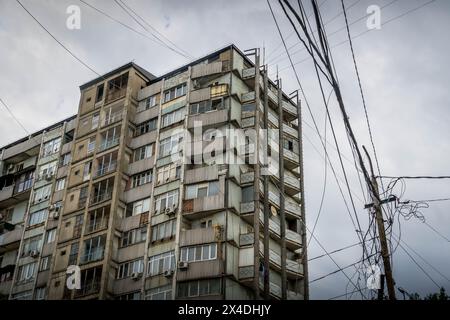 Il vecchio edificio grigio in stile sovietico e la strada si intrecciavano tra i fili nella città di Mahachkala, Repubblica del Daghestan, Russia meridionale Foto Stock