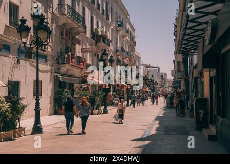 La gente cammina lungo la passeggiata panoramica con edifici in stile coloniale nel centro di Tunisi durante una calda giornata di sole in Tunisia Foto Stock