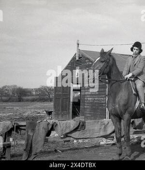 Anni '1960, una ragazza a cavallo alla scuola di equitazione suburbana, Inghilterra, Regno Unito. Foto Stock