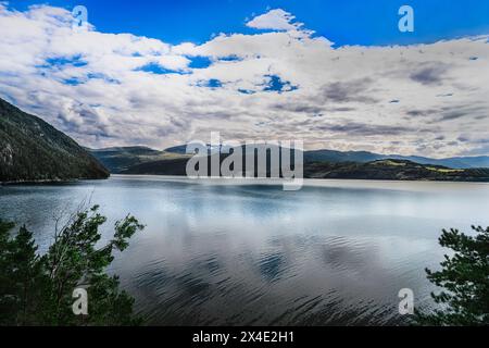 Vista tranquilla su Tingvollfjorden in Norvegia, con acque calme e riflessi sotto un cielo nuvoloso estivo blu. Foto Stock