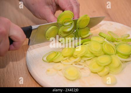 Persona che taglia porri in cucina - porro appena tagliato Foto Stock
