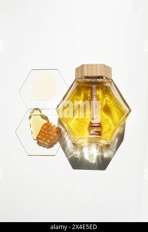 Barattolo e cucchiaio di miele con pettine e gocce Foto Stock