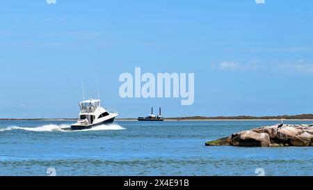 La vista panoramica di uno splendido yacht da pesca bianco e nero naviga oltre la scogliera sulle acque blu calme in una giornata di sole. Foto Stock